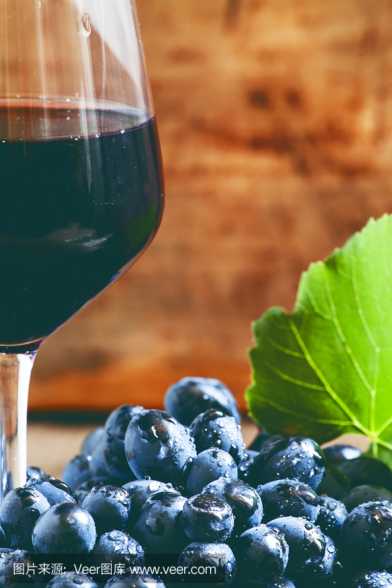 一杯红酒和带叶子的新鲜葡萄